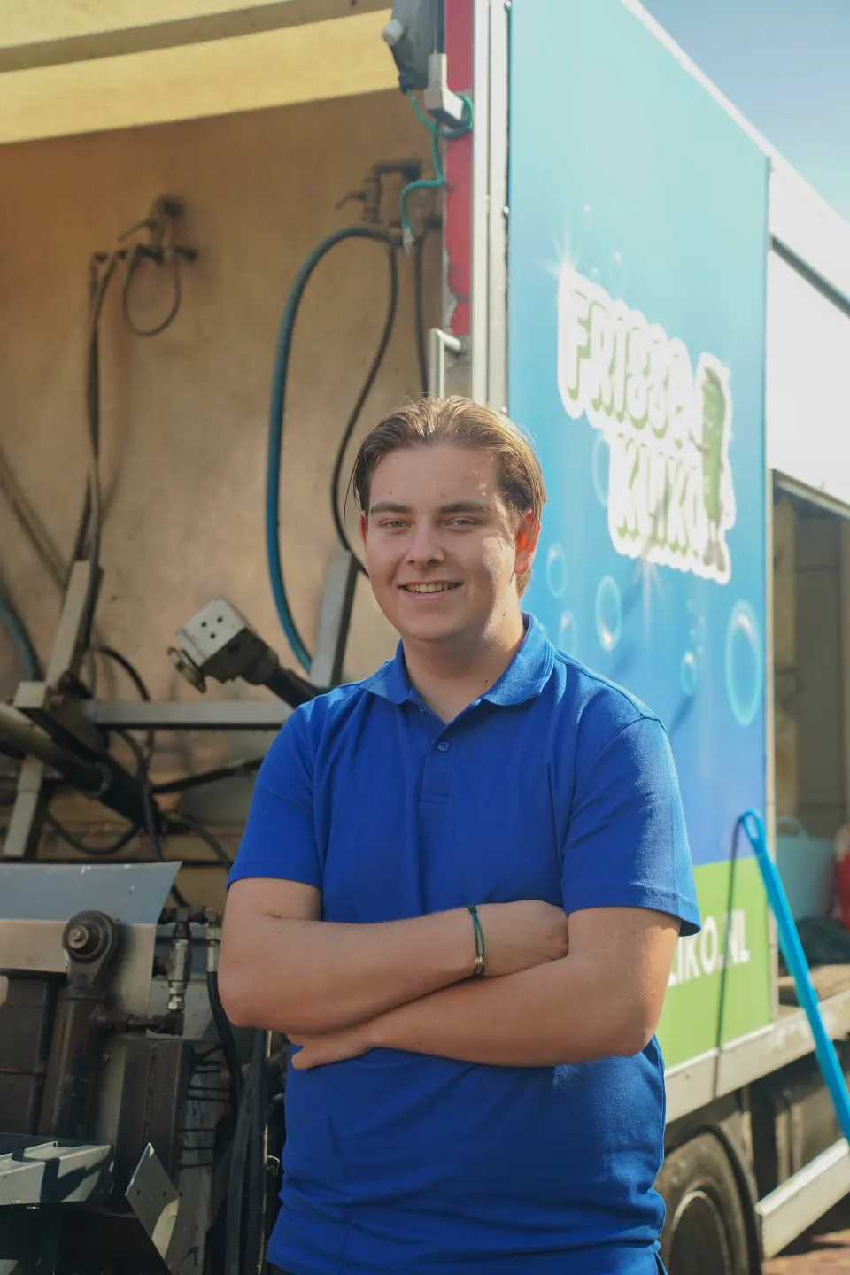 Medewerker van Frisse Kliko met de armen over elkaar voor de reinigingswagen.